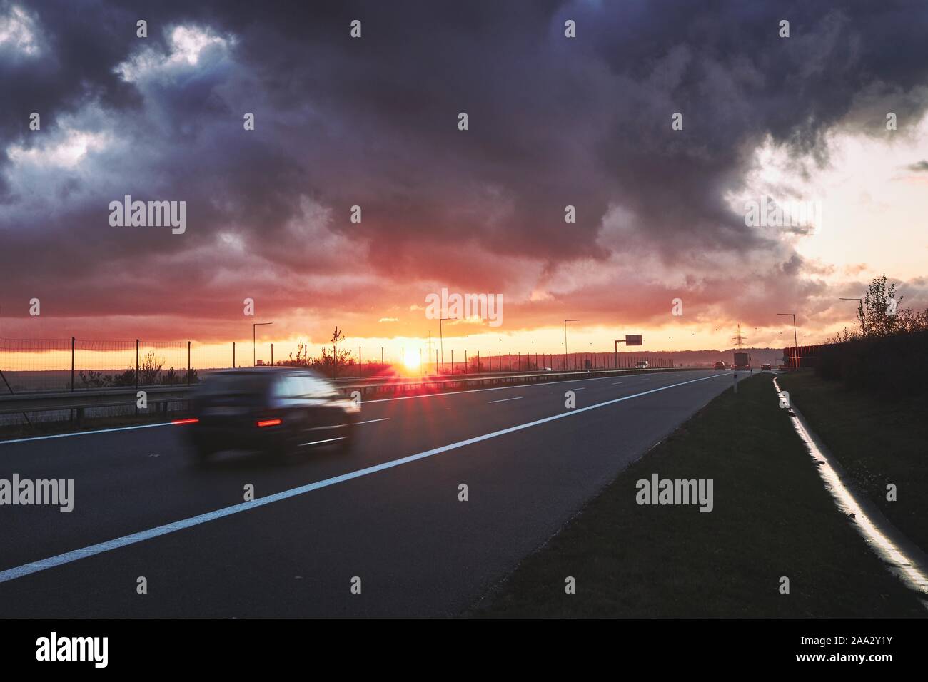 Verschwommene Bewegung des Autos. Der Verkehr auf der Autobahn bei Sonnenuntergang. Stockfoto