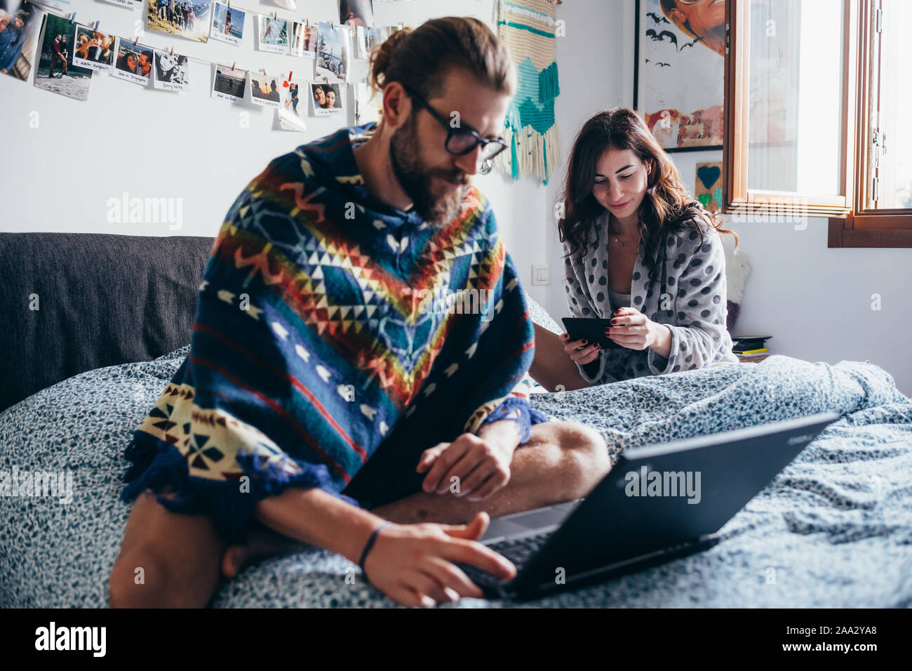 Junges Paar Indoor zu Hause sitzen Bett mit Computer und ebook-Technologie, phubbing, verbundenen Konzept Stockfoto