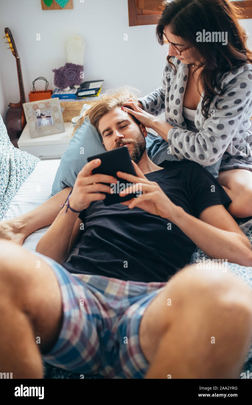 Junge schöne Frau streicheln Haar von bärtigen Mann, während er sich mit Tablet-Liebe, Beziehung, Zärtlichkeit Konzept Stockfoto