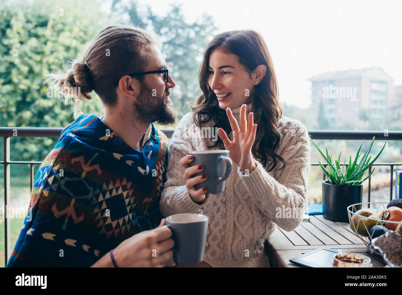 Junges Paar zu Hause Terrasse frühstücken - sie sitzt auf seinem Schoß - Liebe, Beziehung, Romantik Konzept Stockfoto