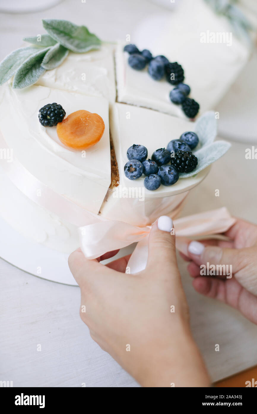 Frau zusammen binden vier Scheiben Kuchen eine zusammengesetzte Kuchen zu machen Stockfoto