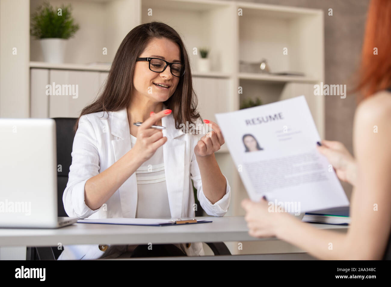 Charmante HR Manager in freundlicher Art und Weise führt ein Interview mit einem der Kandidaten, die auf Post. Selektive konzentrieren. Stockfoto