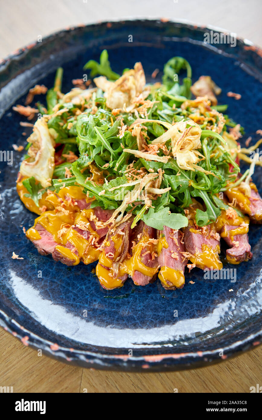 Gebratenes Rindfleisch, Gemüse, Karotte und Austernsauce. In Scheiben geschnitten gegrilltes Rindfleisch Grill Roastbeef Steak und Salat mit Rucola. Stockfoto