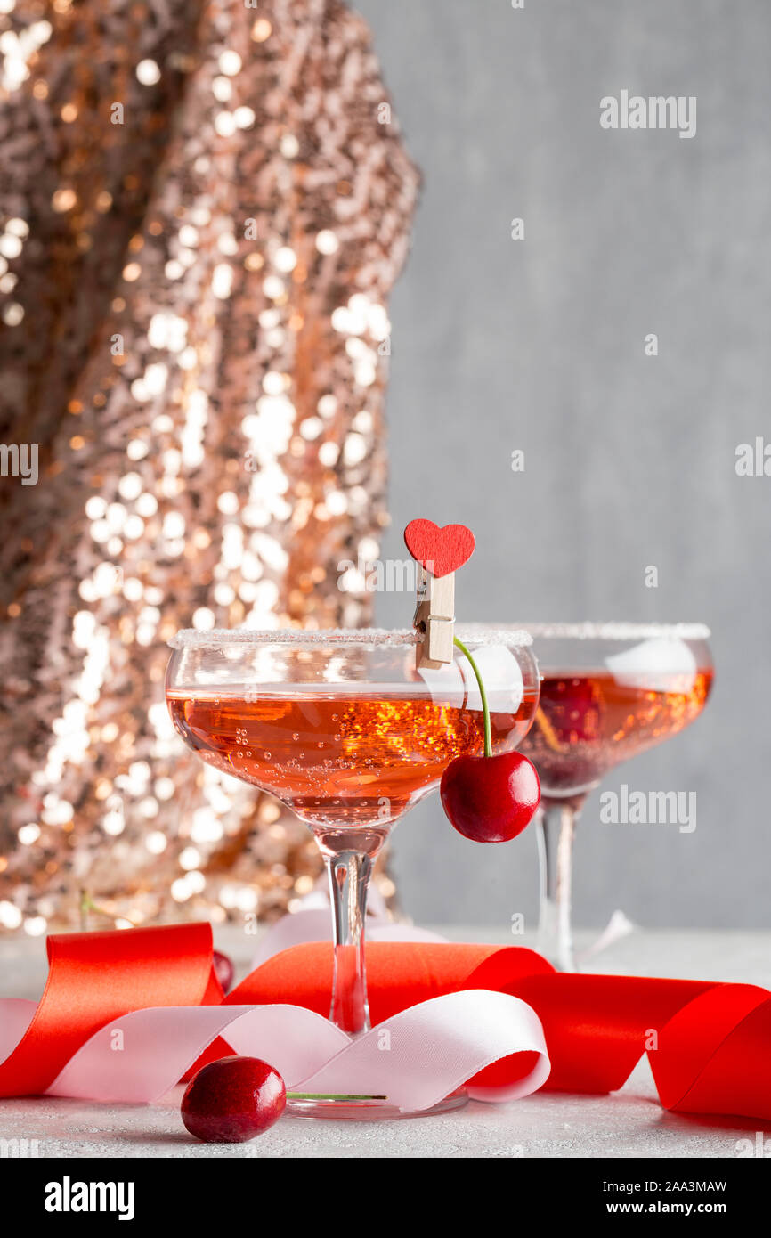 Zwei Gläser mit Champagner Rosé, und Kirsche in festlicher Umgebung. Getränke für Party am Heiligabend, Silvester Party oder Saint Valentine's Day Date. Stockfoto