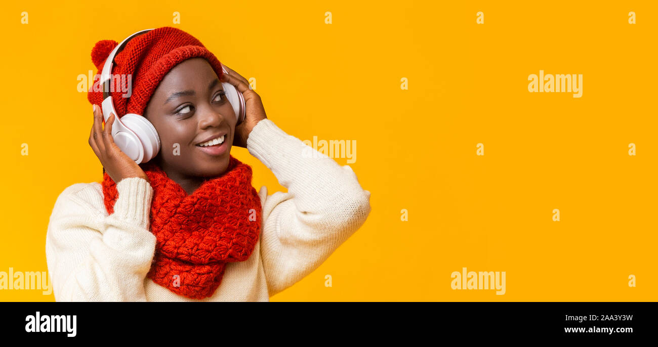 Interessierte schwarze Mädchen mit Kopfhörern auf leeren Raum Stockfoto
