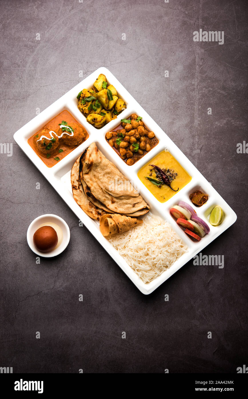 Indische vegetarische Nahrung Thali oder Paket essen - Fach mit Fächern, in denen Malai Kofta, chole, Dal Tarka, chemische aloo Sabji, chapati und Reis mit süßer Stockfoto