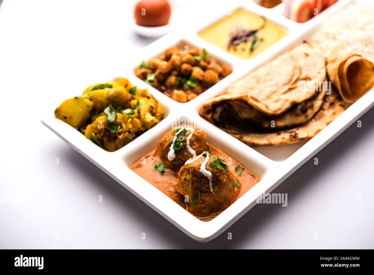 Indische vegetarische Nahrung Thali oder Paket essen - Fach mit Fächern, in denen Malai Kofta, chole, Dal Tarka, chemische aloo Sabji, chapati und Reis mit süßer Stockfoto