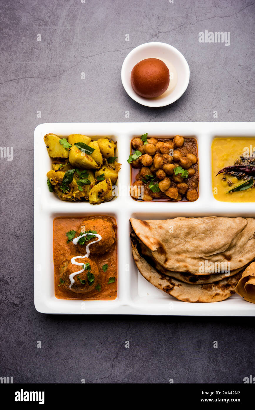 Indische vegetarische Nahrung Thali oder Paket essen - Fach mit Fächern, in denen Malai Kofta, chole, Dal Tarka, chemische aloo Sabji, chapati und Reis mit süßer Stockfoto