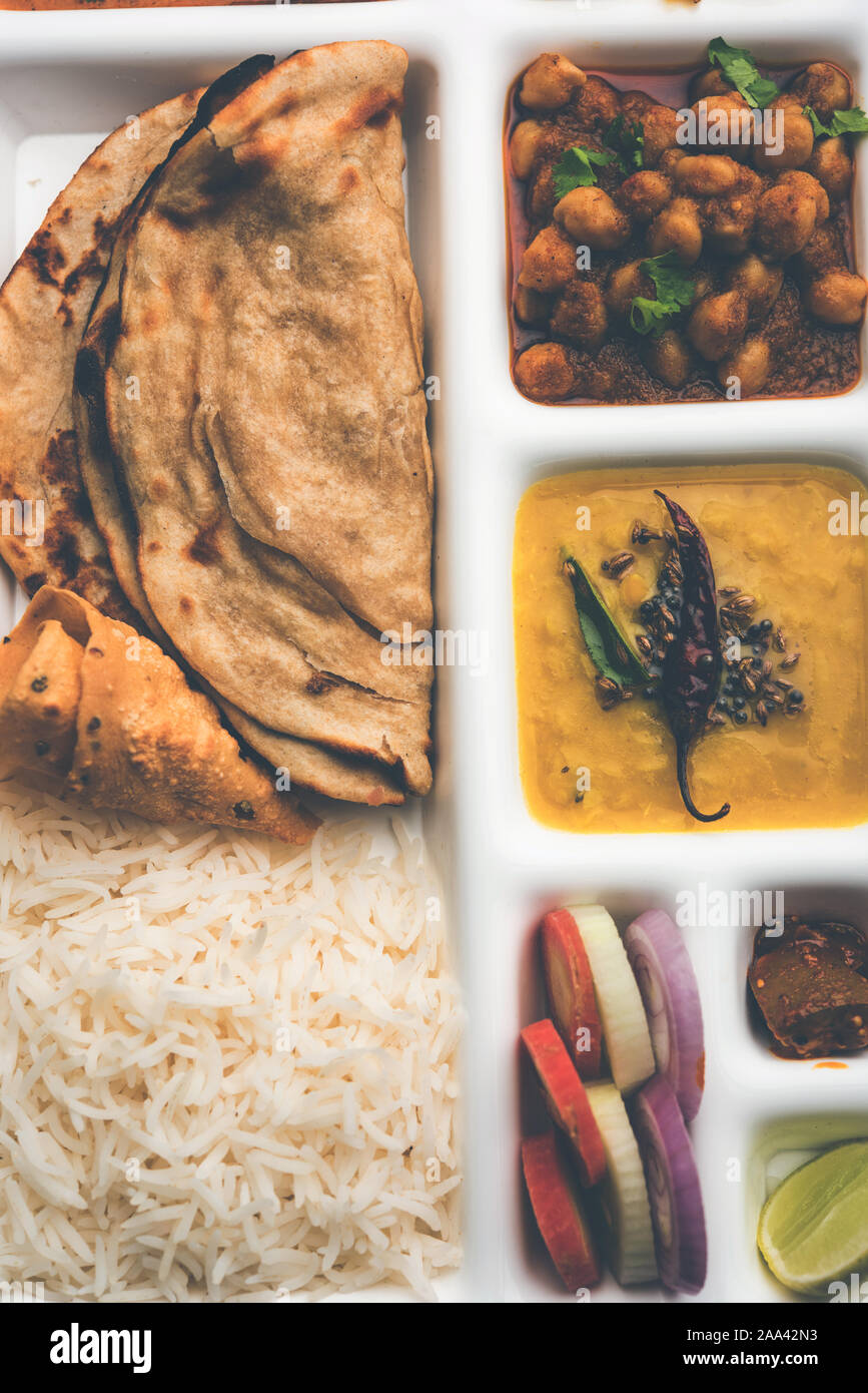 Indische vegetarische Nahrung Thali oder Paket essen - Fach mit Fächern, in denen Malai Kofta, chole, Dal Tarka, chemische aloo Sabji, chapati und Reis mit süßer Stockfoto