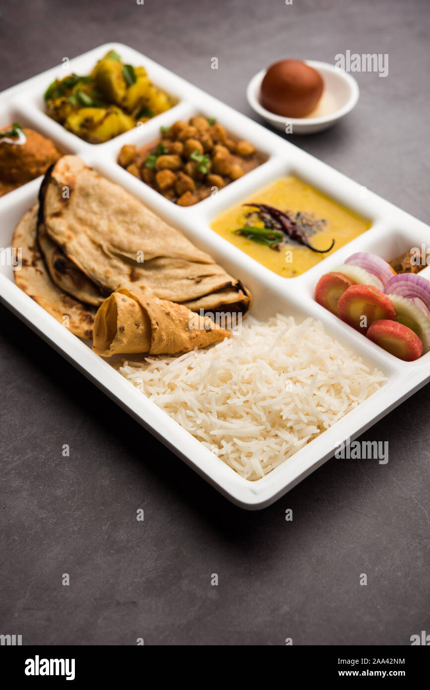 Indische vegetarische Nahrung Thali oder Paket essen - Fach mit Fächern, in denen Malai Kofta, chole, Dal Tarka, chemische aloo Sabji, chapati und Reis mit süßer Stockfoto
