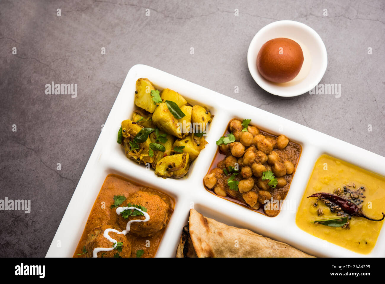 Indische vegetarische Nahrung Thali oder Paket essen - Fach mit Fächern, in denen Malai Kofta, chole, Dal Tarka, chemische aloo Sabji, chapati und Reis mit süßer Stockfoto