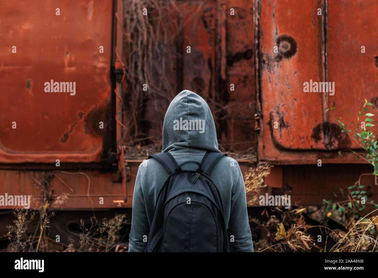 Obdachlose Frau mit Rucksack Entfliehen, Rückansicht der weiblichen Fuß unter verlassenen Waggons und veraltete Eisenbahn Stockfoto