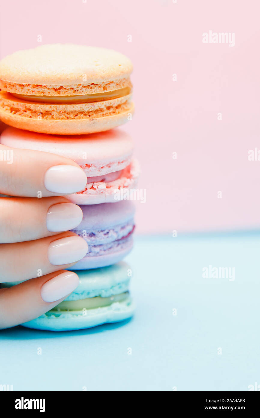 Schönheit hand Mädchen mit trendigen Maniküre unter Farbe makronen auf blauem Hintergrund. Stockfoto