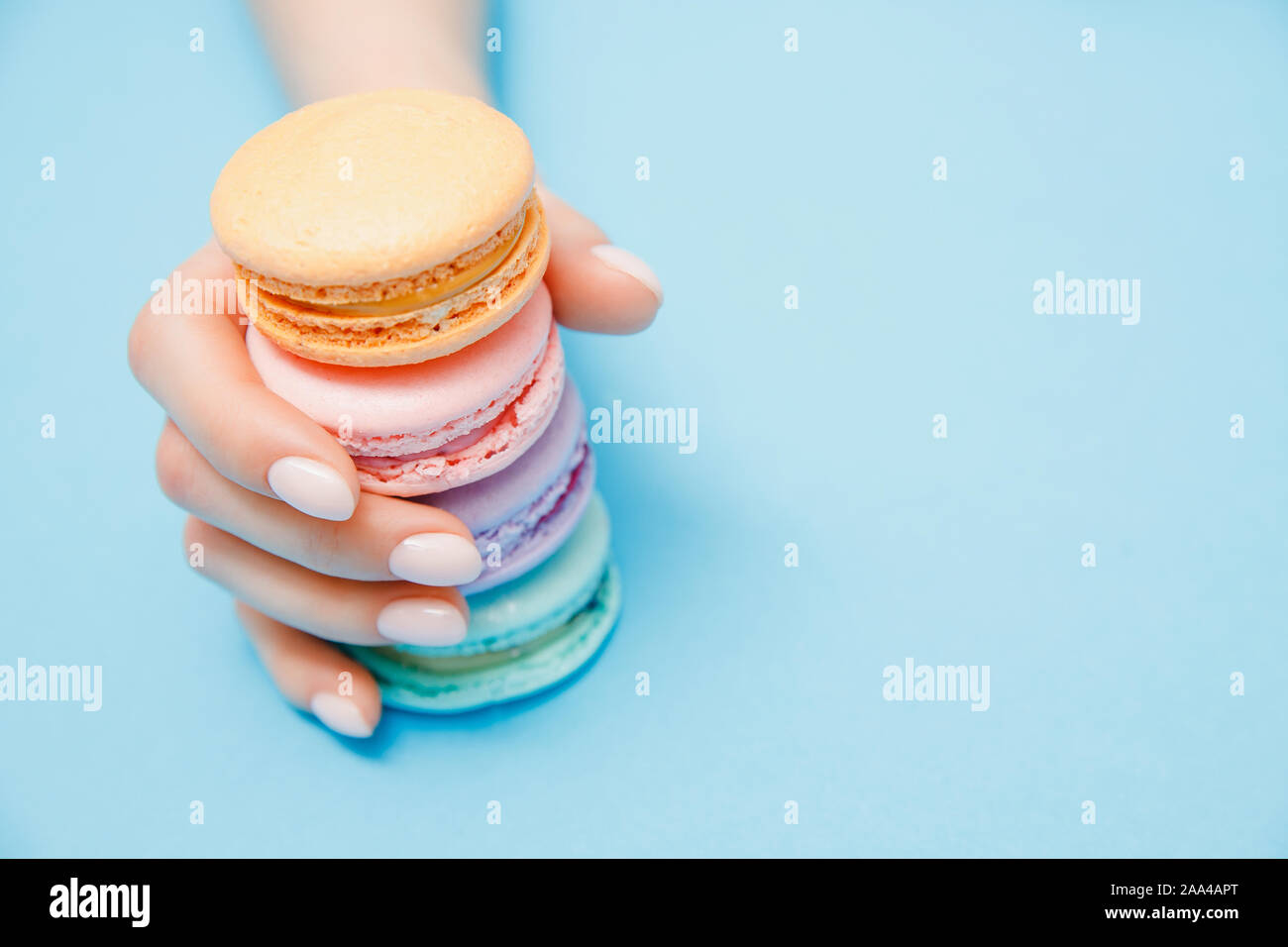 Schönheit hand Mädchen mit trendigen Maniküre unter Farbe MACARONS auf blauem Hintergrund. Stockfoto