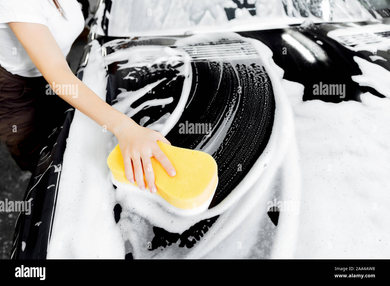 Hintergrund Hand halten Schwamm über schwarzen Auto waschen weißer Schaum. Stockfoto
