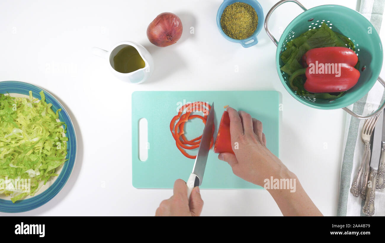Roter Pfeffer Schichten in der Nähe auf einem Schneidebrett. Salat auf einen Teller, auf weißem Hintergrund schliessen. Frische organische Römersalat, rot Pfeffer, auf Stockfoto