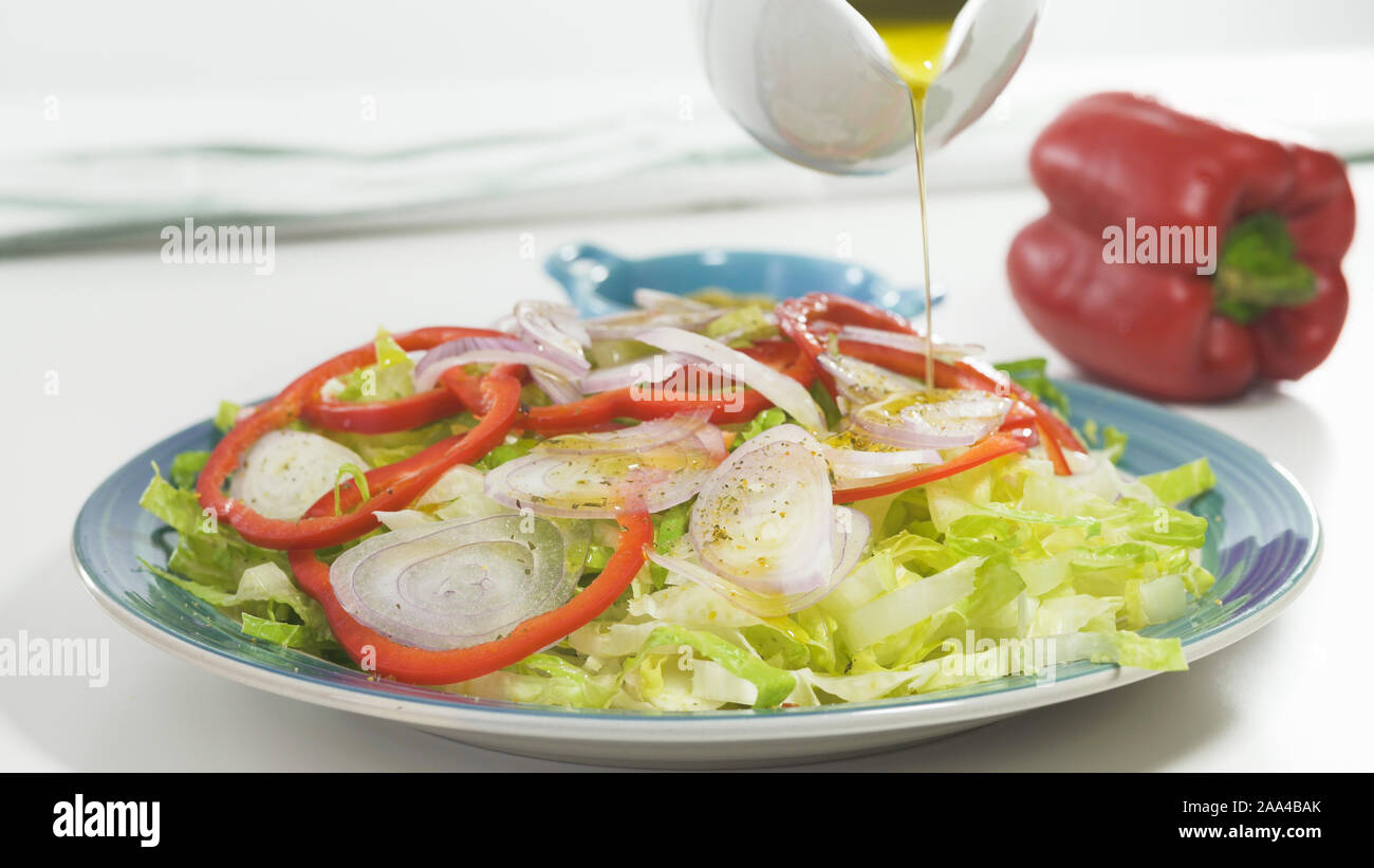 Salat auf einen Teller, auf weißem Hintergrund schliessen. Frische organische Römersalat, Paprika, Zwiebel, einige Gewürze und Olivenöl. Stockfoto