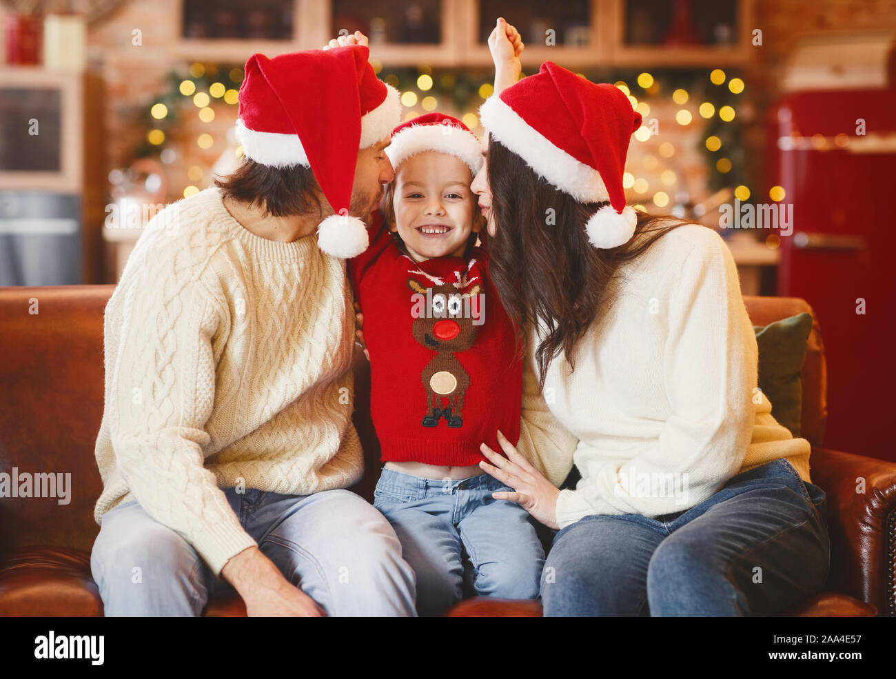 Festliche Eltern küssen glücklich, kleines Mädchen, Weihnachten gemeinsam feiern. Stockfoto