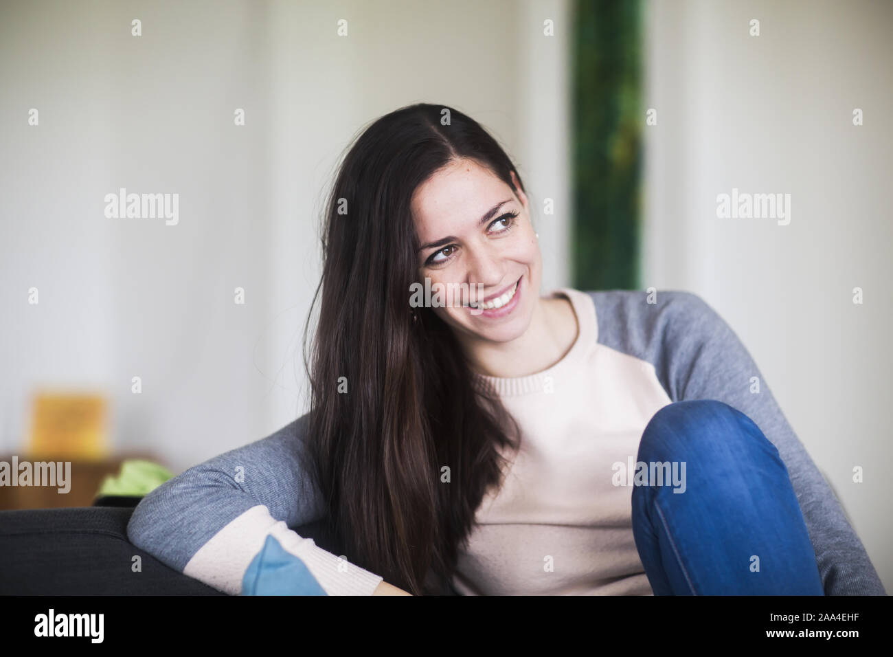 Lächelnde Frau auf einem Sofa sitzt Stockfoto