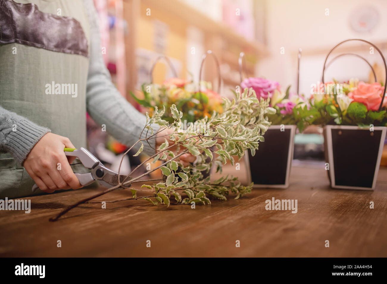Florist Mädchen im Vorfeld sammelt Blumenstrauß aus Rosen Blumen in Geschenkbox, Schnitte Blätter mit Baum-, Reb- und Gartenscheren. Stockfoto