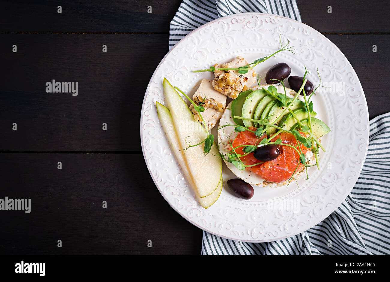 Gesundes Frühstück. Sandwiches mit Frischkäse, Lachs, Avocado und Scheibe Birne an der Platte. Ansicht von oben, Overhead Stockfoto