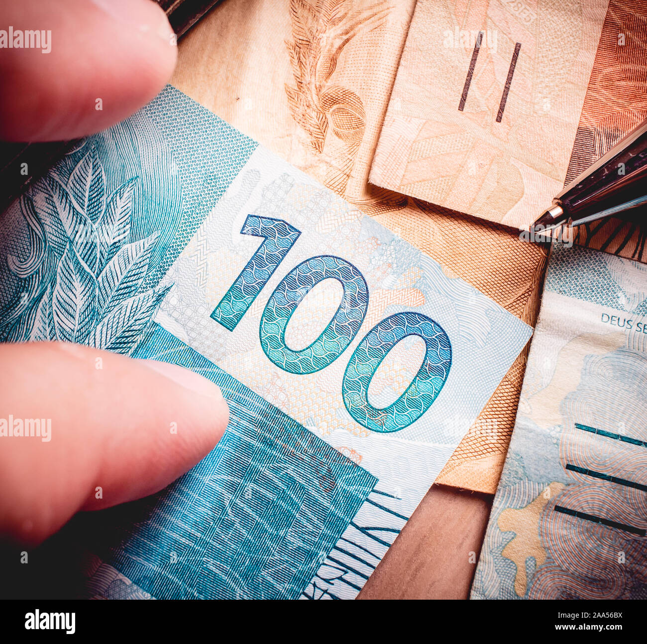 Real-brasilianischen Währung. Geld wechsel auf einem Holztisch und ein Mann mit einem Banknoten. Stockfoto