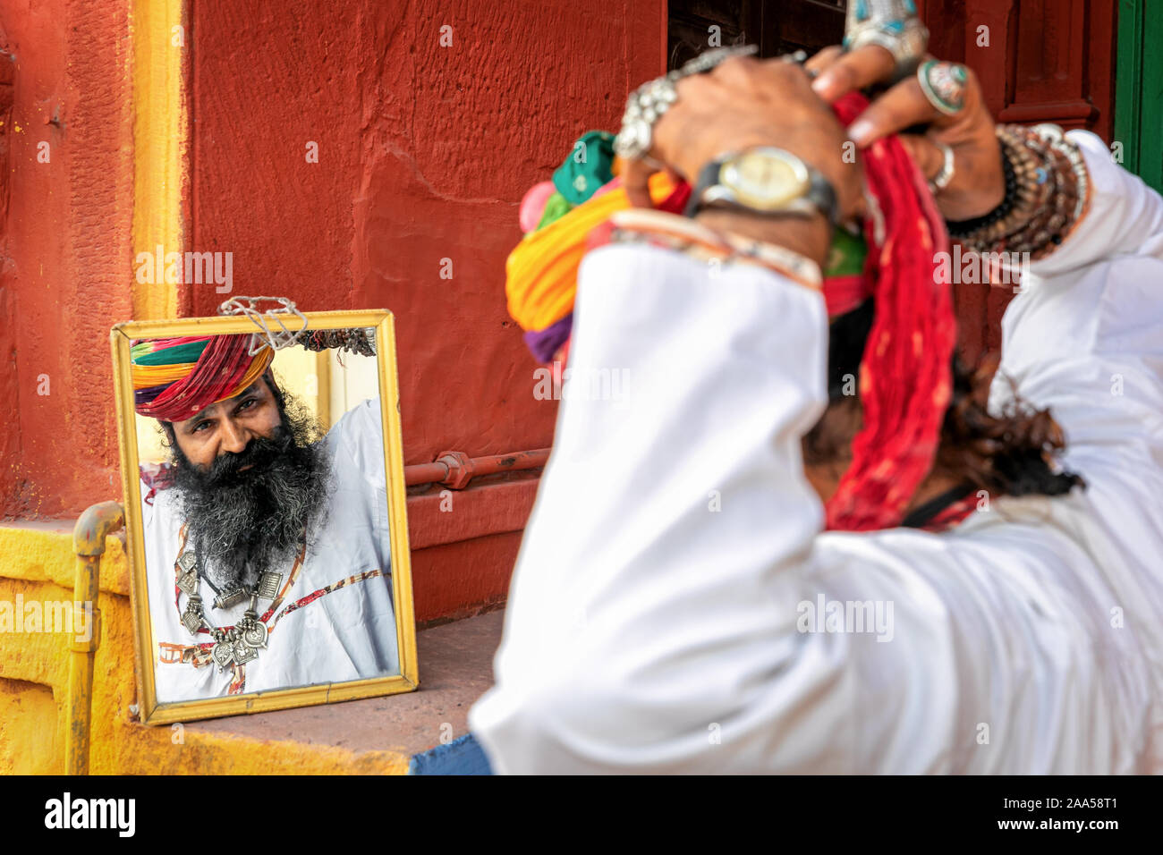 Mann bin auf seine Reflexion in einem Spiegel, wenn Binden seinen Turban, Jodhpur, Rajasthan, Indien Stockfoto