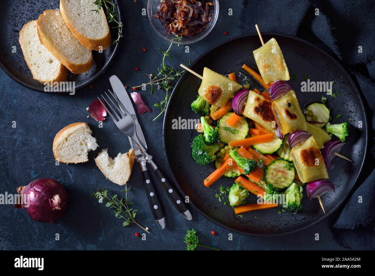 Gebratene schwäbische Fleisch Ravioli Spieße mit gebuttertem Gemüse und gerösteten Zwiebeln serviert Stockfoto