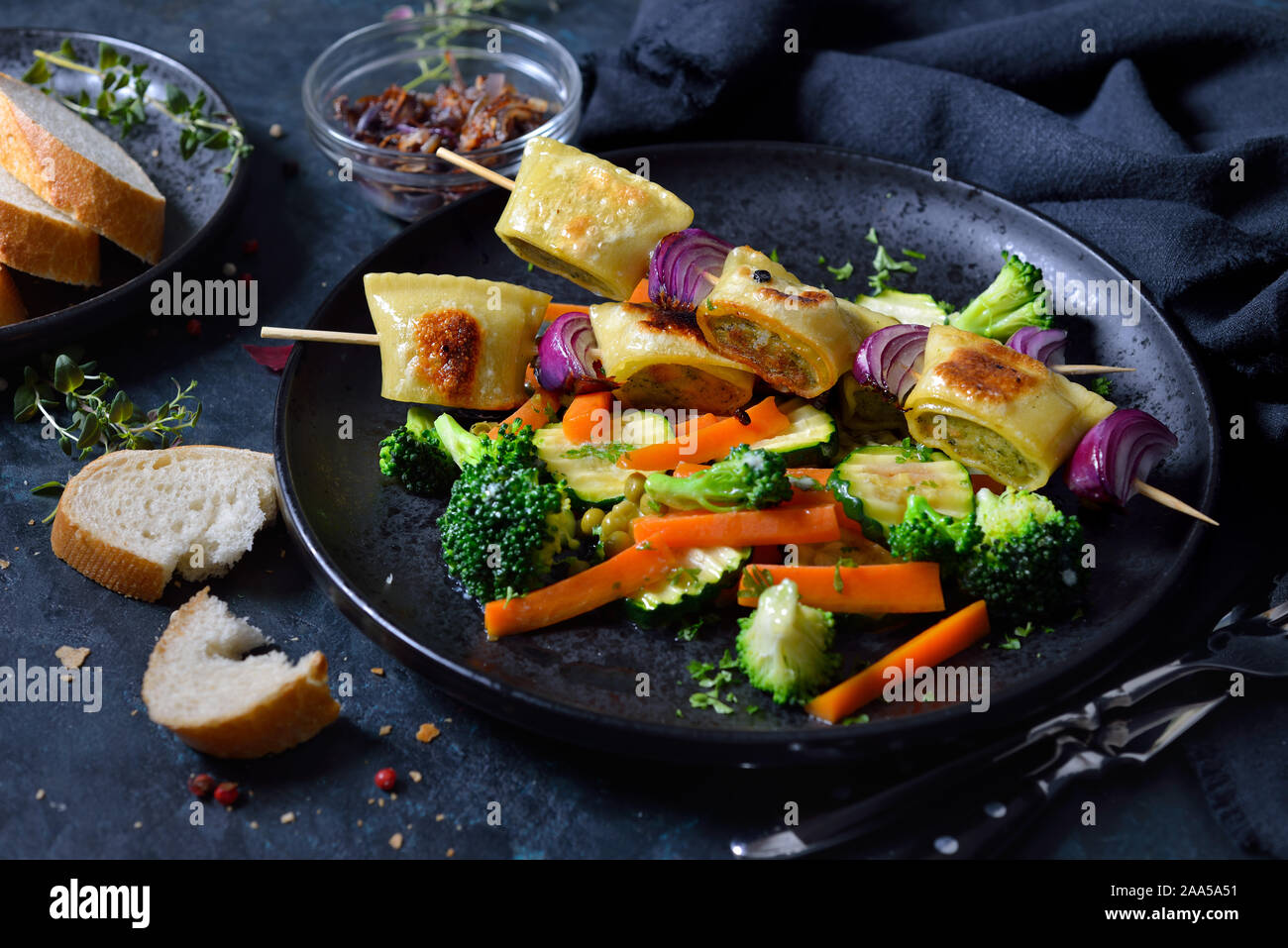 Gebratene schwäbische Fleisch Ravioli Spieße mit gebuttertem Gemüse und gerösteten Zwiebeln serviert Stockfoto