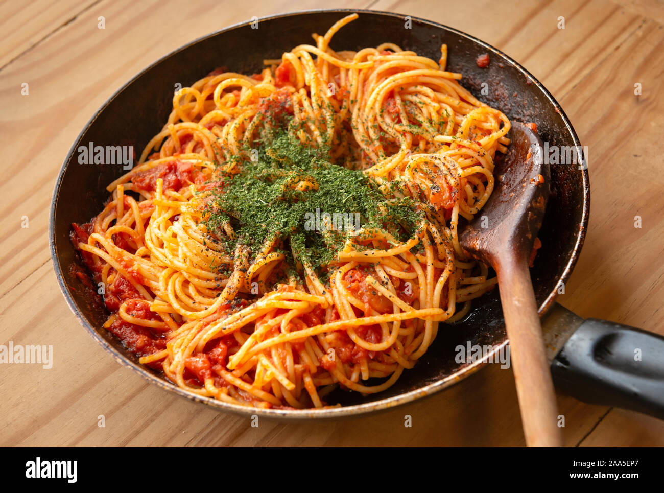 Traditionelle vintage gekochten spaghetti Pasta in Tomatensauce und Kräuter mit Holzlöffel im rustikalen Pfanne. Stockfoto