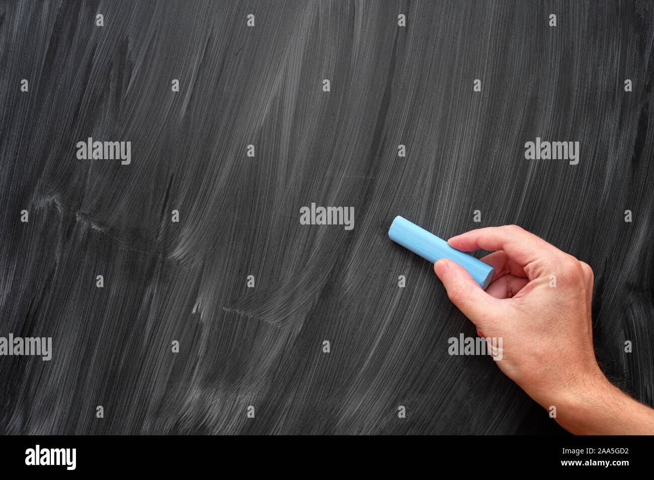 Hand mit blauer Kreide auf einer schwarzen Tafel. Close Up. Stockfoto