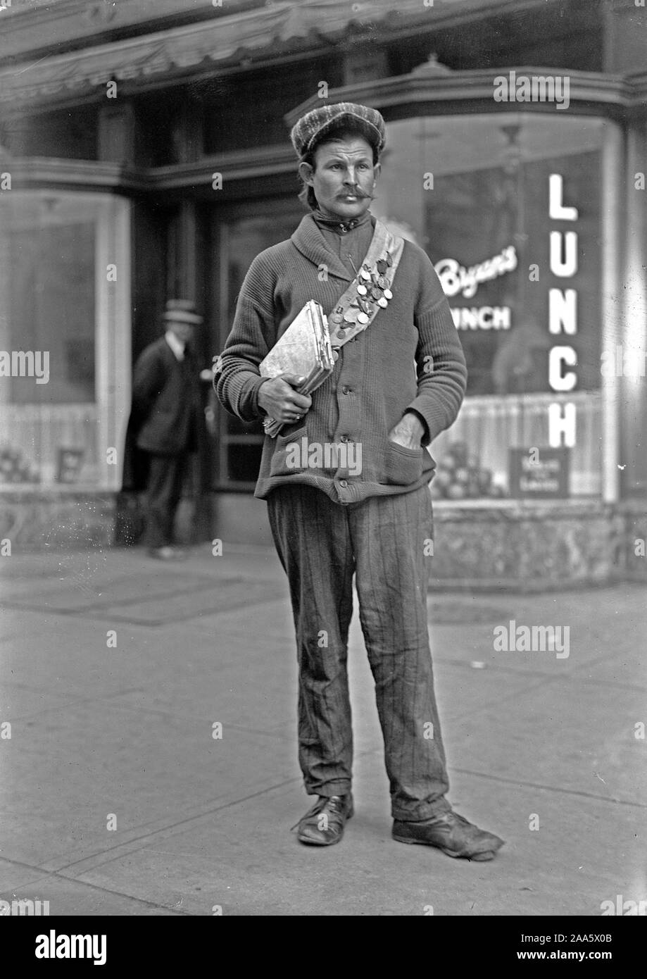 1900 Der Mensch in der amerikanischen Stadt holding Bücher oder Zeitungen und das Tragen einer Medaille Schärpe abgedeckt Stockfoto