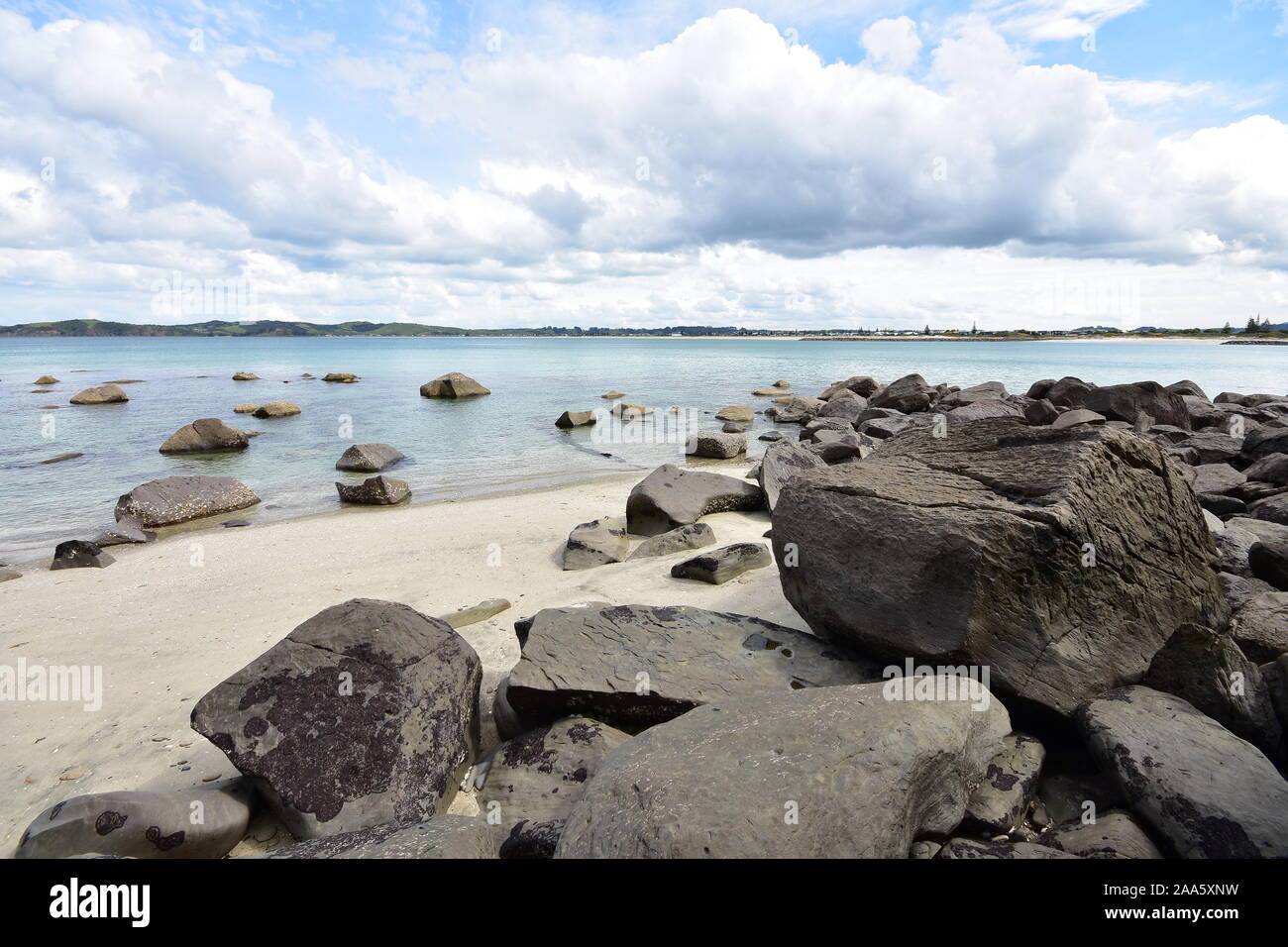 Sandstrand mit großen Steinen, sowohl an der Küste und in klaren Flachwasser. Stockfoto