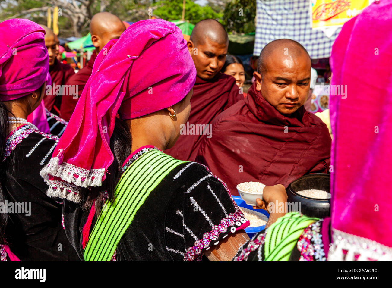 Eine Gruppe junger Frauen, die ethnischen Minderheiten angehören, Almosen/Spenden an lokale Buddhistische Mönche Im Pindaya Cave Festival, Pindaya, Shan Staat, Myanmar. Stockfoto