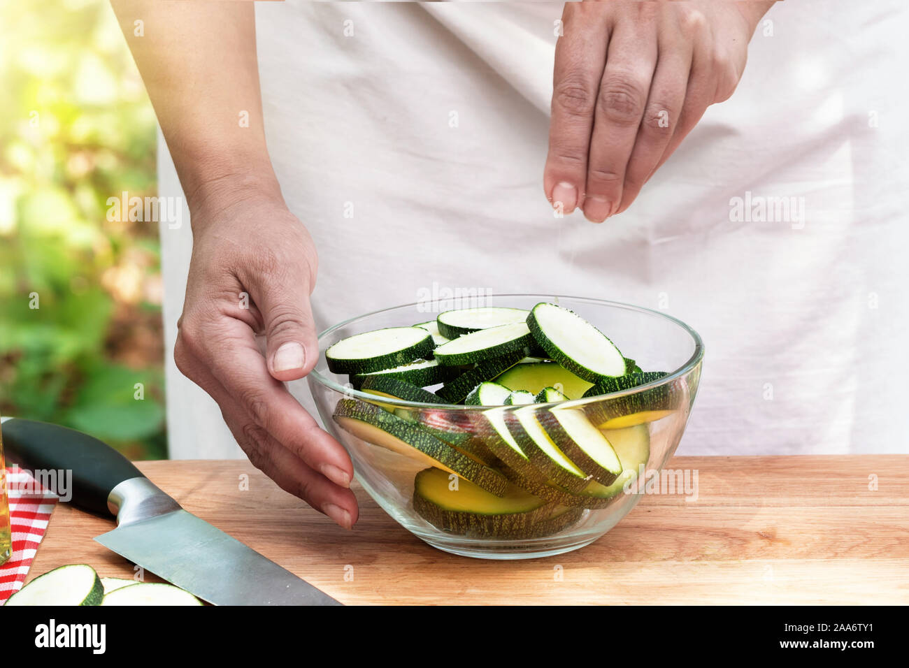 Weibliche Hände Salz geschnittene Zucchini in einer Glasschale. Sommer sonnigen Tag Stockfoto