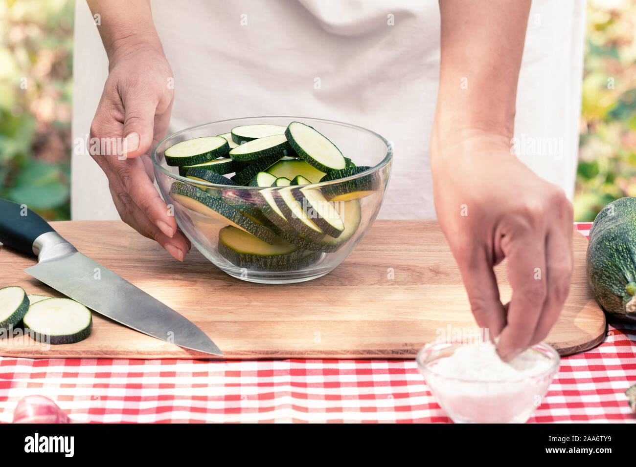 Weibliche Hände Salz geschnittene Zucchini auf einem Holzbrett. Sommer sonnigen Tag Stockfoto