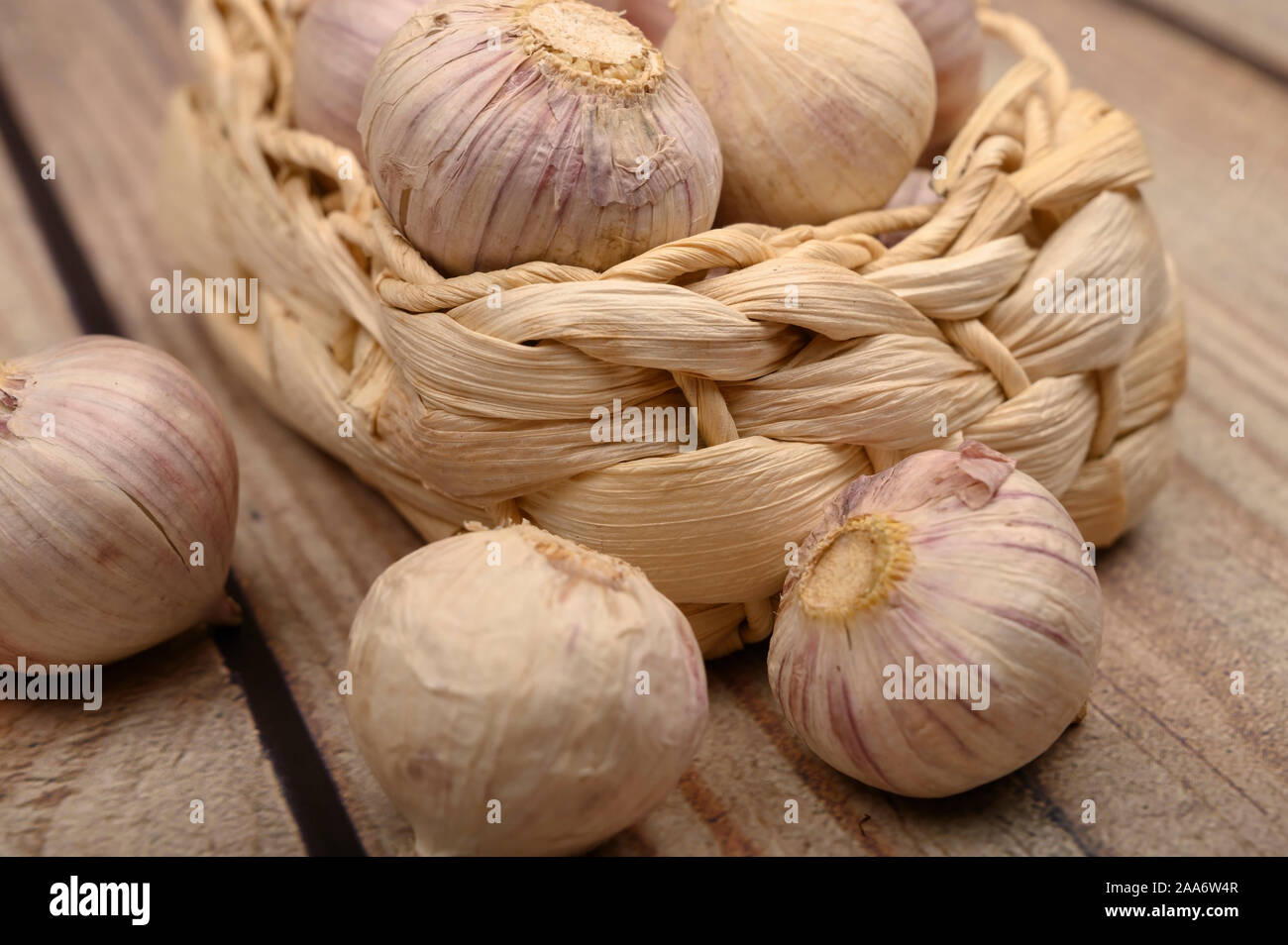 Ein paar Köpfe junger Knoblauch in einem Weidenkorb auf einer hölzernen Hintergrund. Herbst Ernte. Die moderne Landwirtschaft. Nahaufnahme Stockfoto