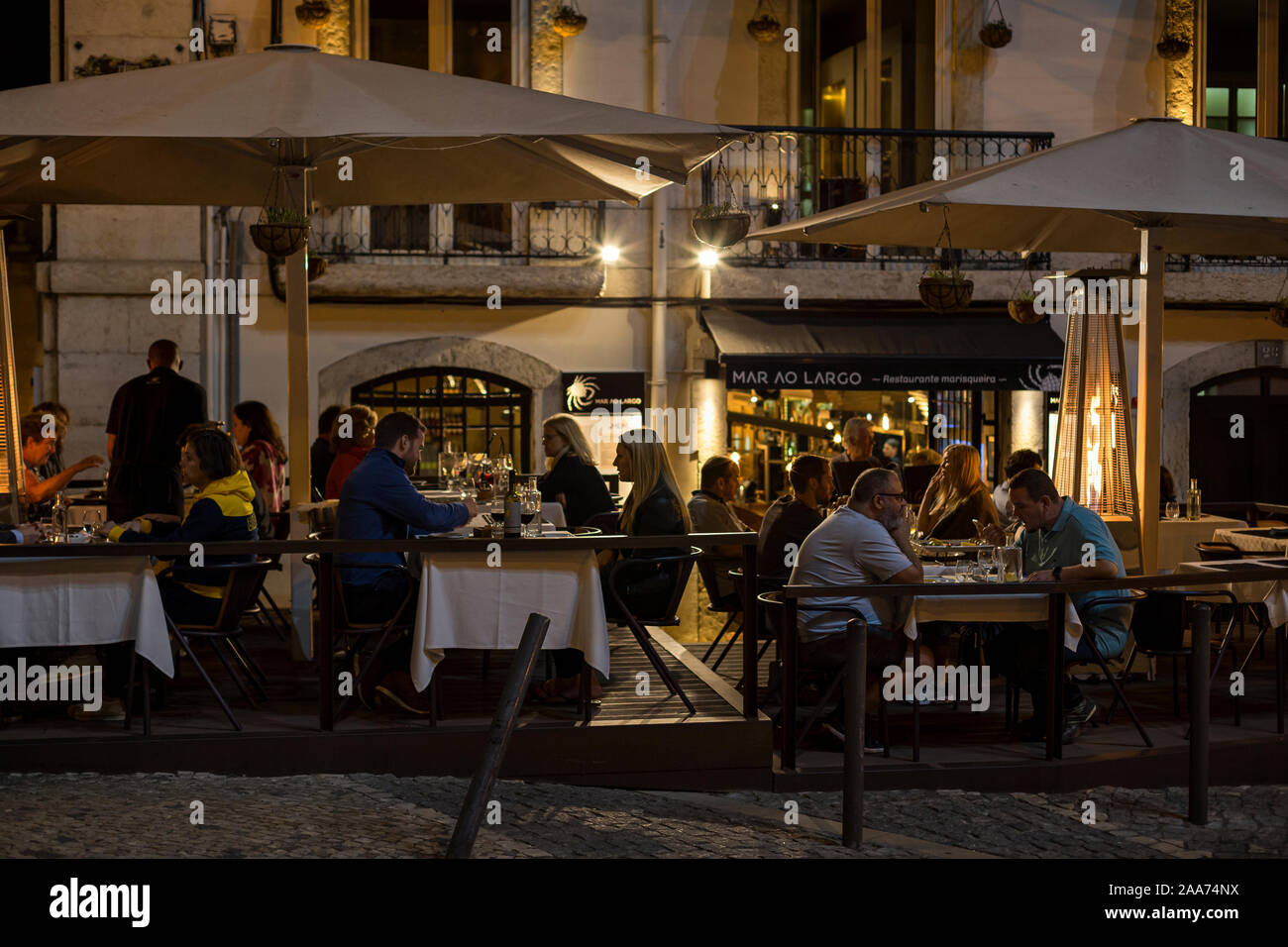 Die Menschen essen im Freien auf der Largo Rafael Bordalo Pinheiro Straße im Stadtteil Bairro Alto in Lissabon, Portugal, am Abend. Stockfoto