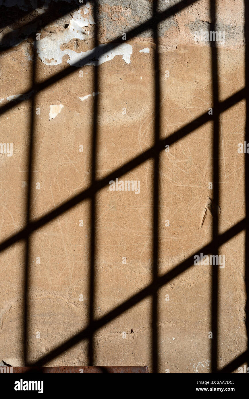 Schattenmuster auf alte Mauer aus Metallstangen oder Iron-Barred Windows im ehemaligen Gefängnis oder Gefängniszelle Stockfoto