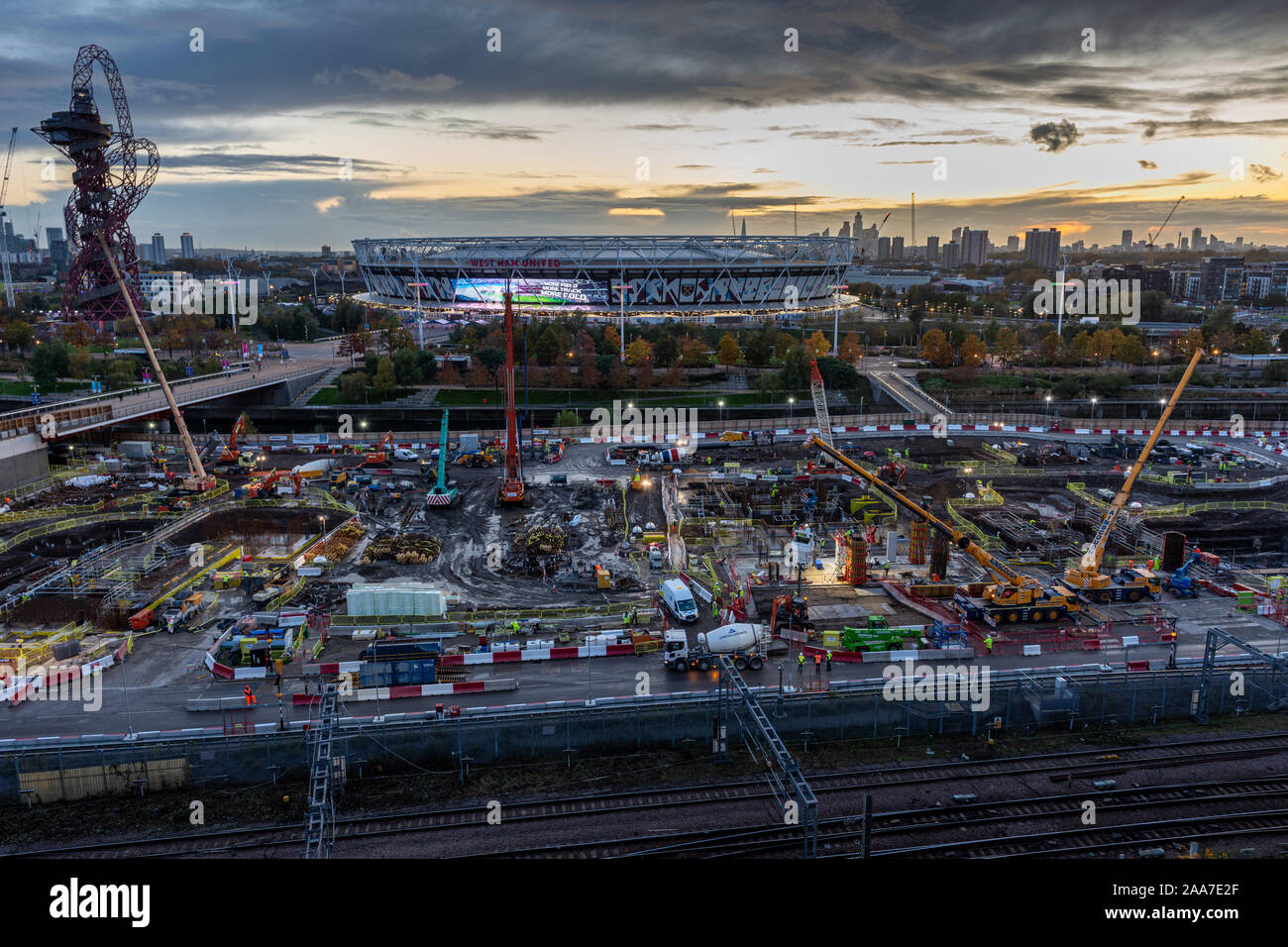 London, England, Großbritannien - 4. November 2019: Bauherren gießen Beton auf einer Baustelle im Olympischen Park mit dem Londoner Stadion und Skyline hinter sich. Stockfoto
