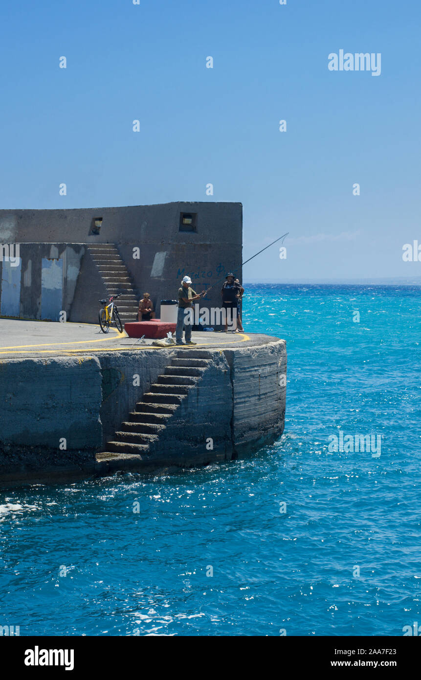 Heraklion, Kreta, Griechenland - 14. Juli 2018: Die Gruppe der lokalen griechischen Fischer auf der Seebrücke Angeln mit Angelruten. Vertikale Ausrichtung. Stockfoto