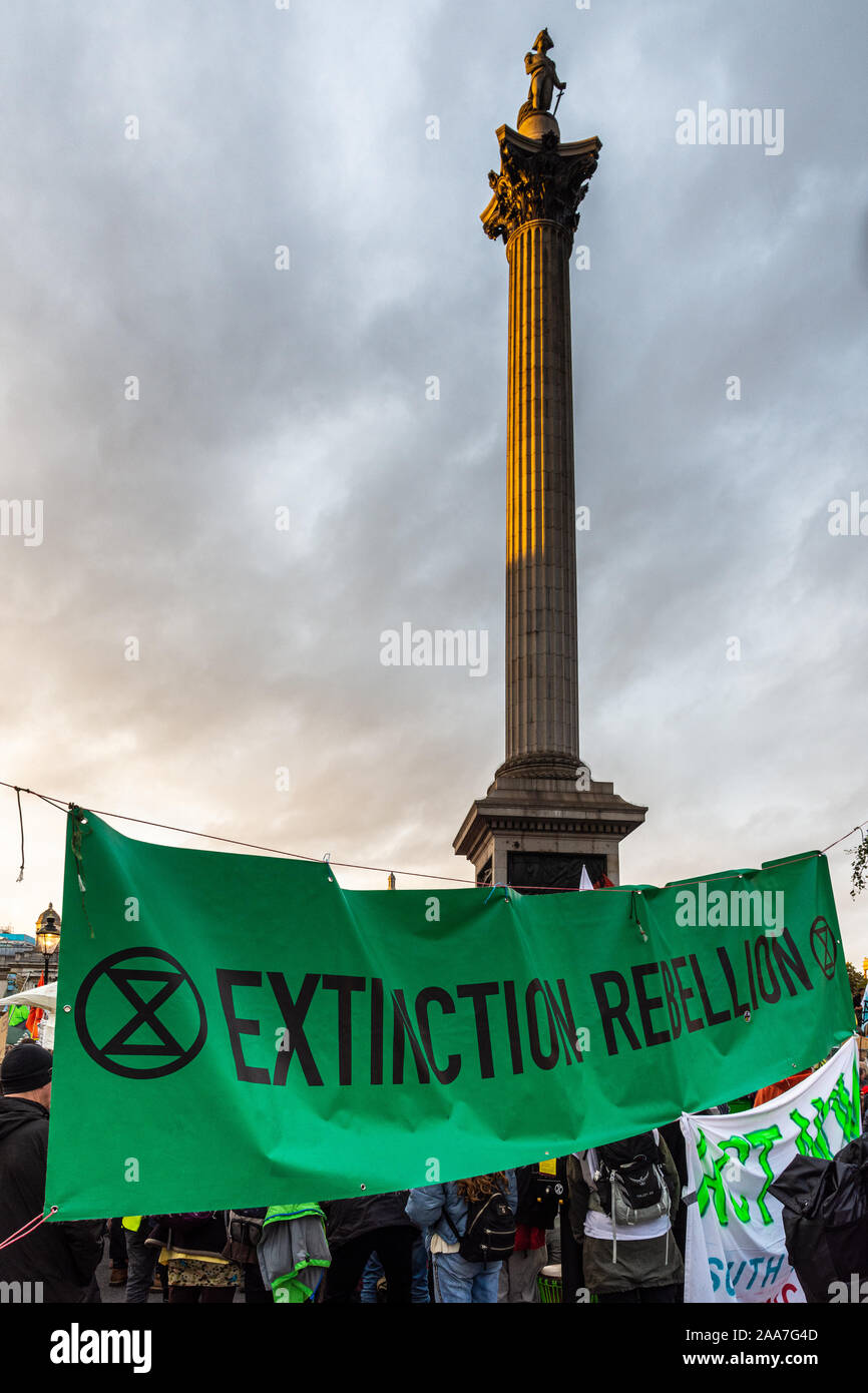 London, England, UK - 10. Oktober 2019: Nelson's Column erhebt sich über einem Protest Fahne während Aussterben Rebellion Aktion auf dem Trafalgar Square in London. Stockfoto