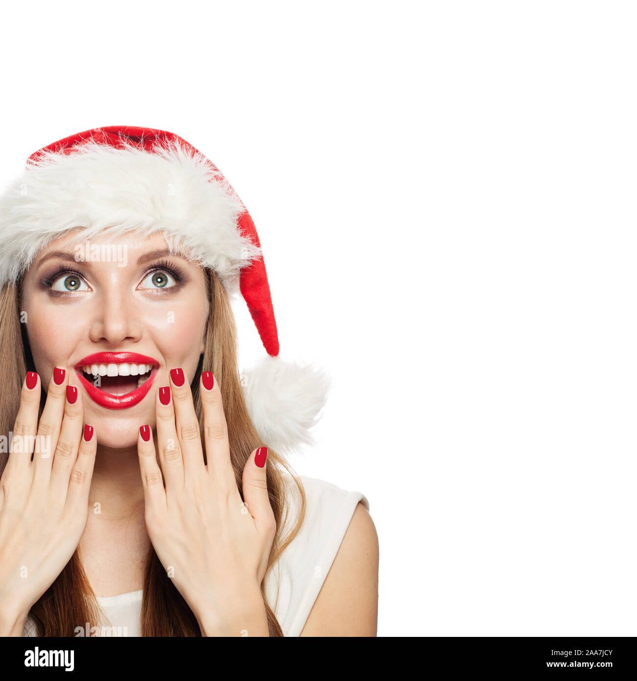 Glückliche Frau in Santa Hut mit roten Maniküre Nägel in der Nähe von roten Lippen isoliert. Überrascht Weihnachten Mädchen suchen Stockfoto