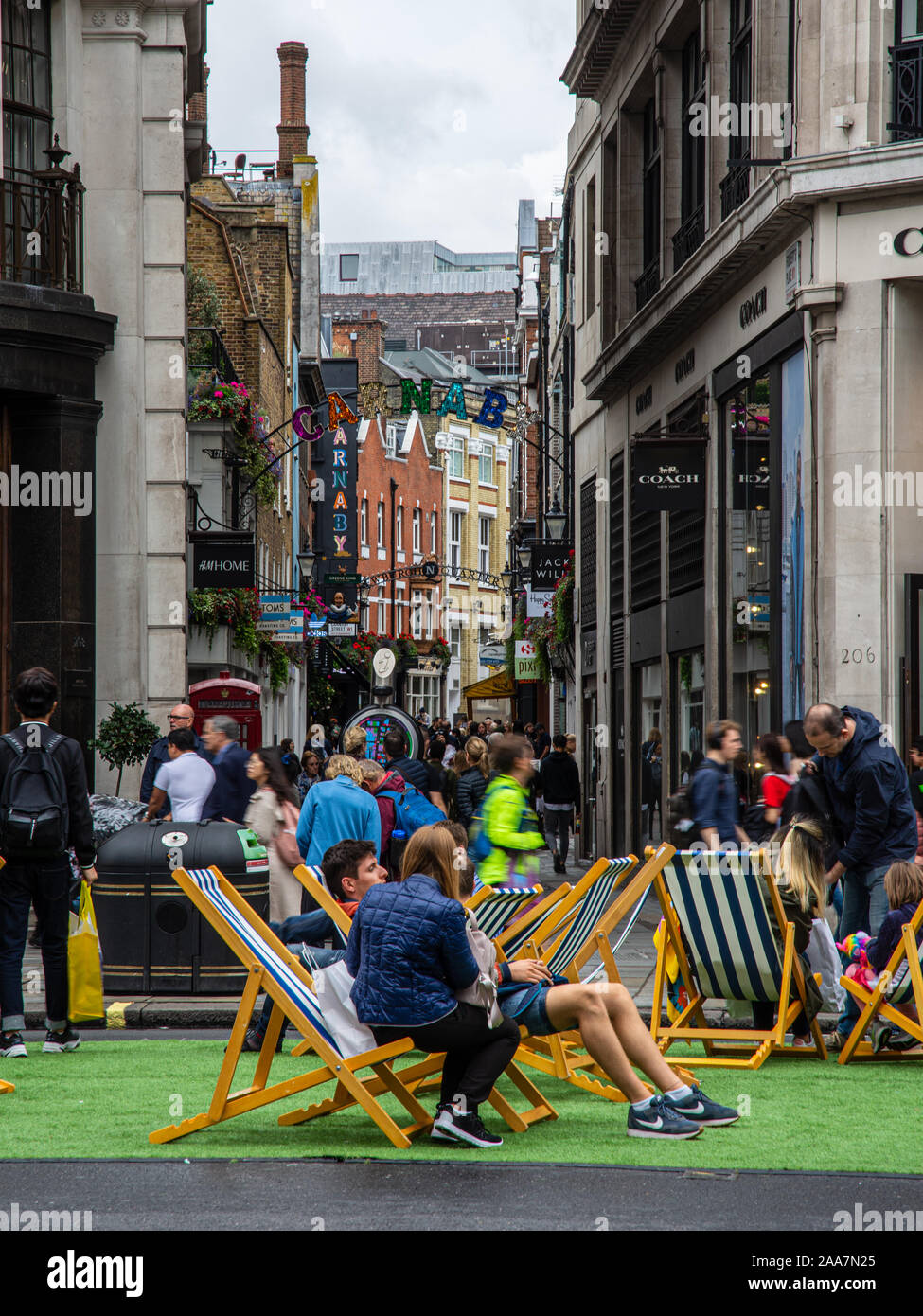 London, England, Großbritannien - 22 September, 2019: Käufer Spaziergang entlang der Carnaby Street und auf Liegestühlen auf Regents Street in London's Autofreie Tag Eva sitzen Stockfoto
