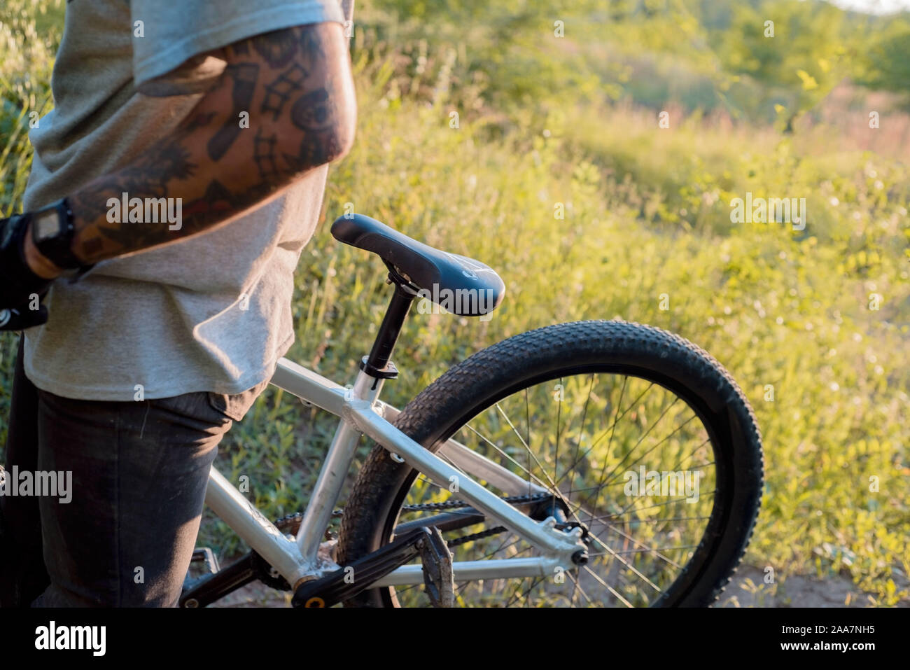 Jungen athletischen Mann in einem schwarzen T-Shirt und Blue Jeans Shorts auf dem Sport Fahrrad auf einem hellen Herbst Hintergrund. Das Bild zeigt das Fragment eines bicy Stockfoto