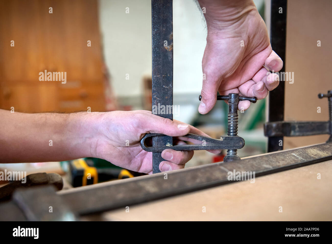 Tischler, mit denen Holz in einen Schraubstock auf der Werkbank Festziehen der Schraube in einer Nahaufnahme auf seinen Händen Stockfoto