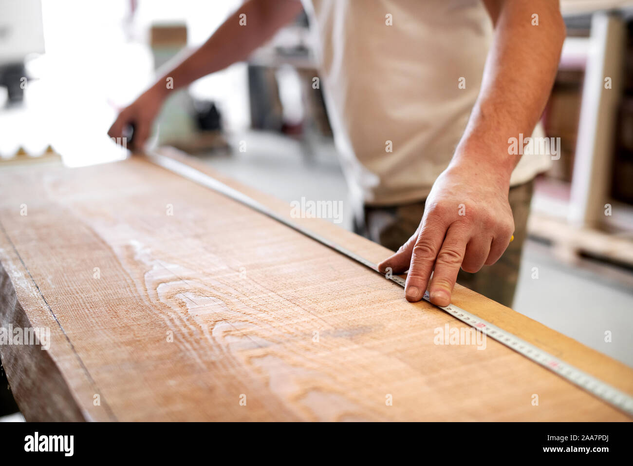 Tischler mit einem Maßband in einem Workshop die Länge einer Planke aus Holz mit selektiven Fokus auf seine Hand zu messen. Stockfoto