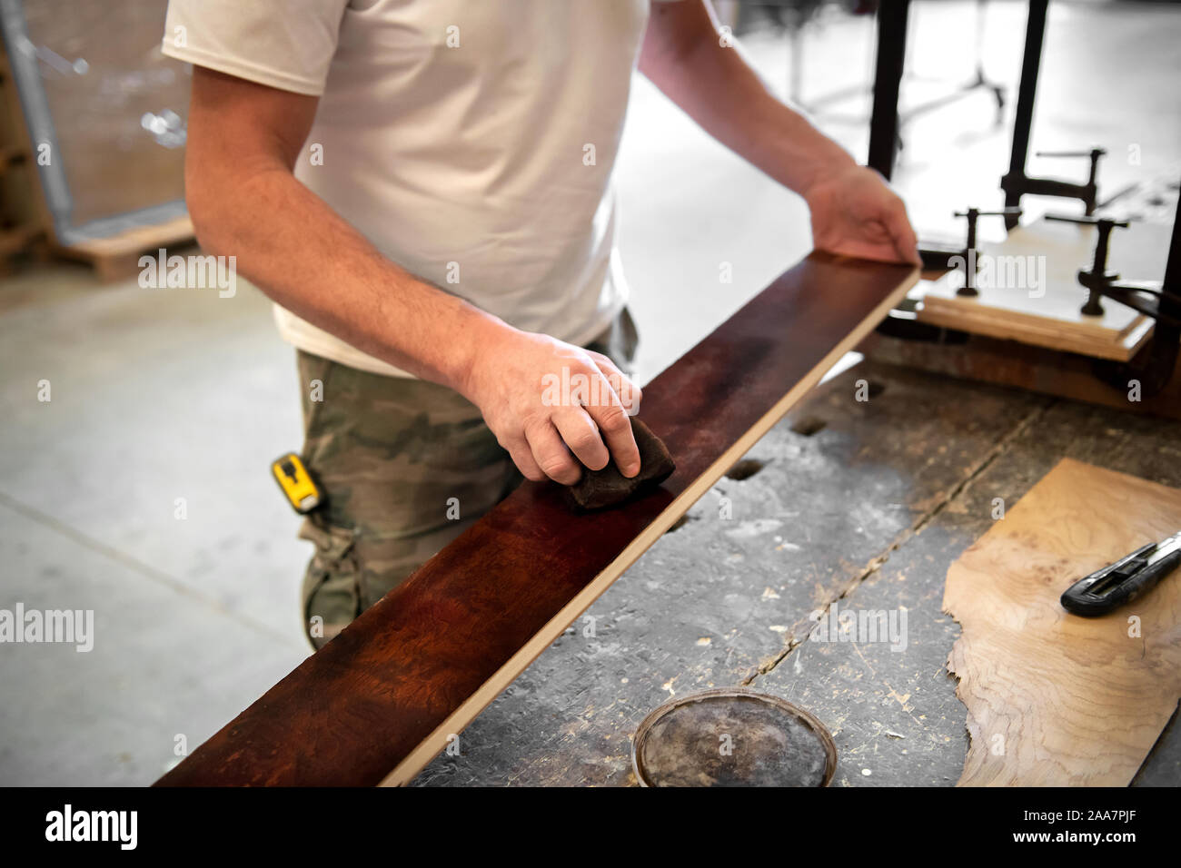 Tischler oder Schreiner Färbung oder Färbung eine briar root-Panel in Nahaufnahme auf der Planke des Holzes und seine Hände über die Workbench Stockfoto