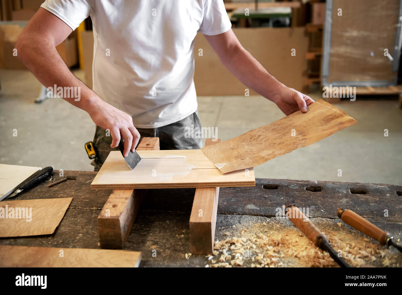 Tischler Auftragen von Leim ein Panel von briar root Furnier zu einem Block Holz in einer Holz verarbeitenden Fabrik oder Werkstatt zu befestigen, die während der Herstellung Stockfoto