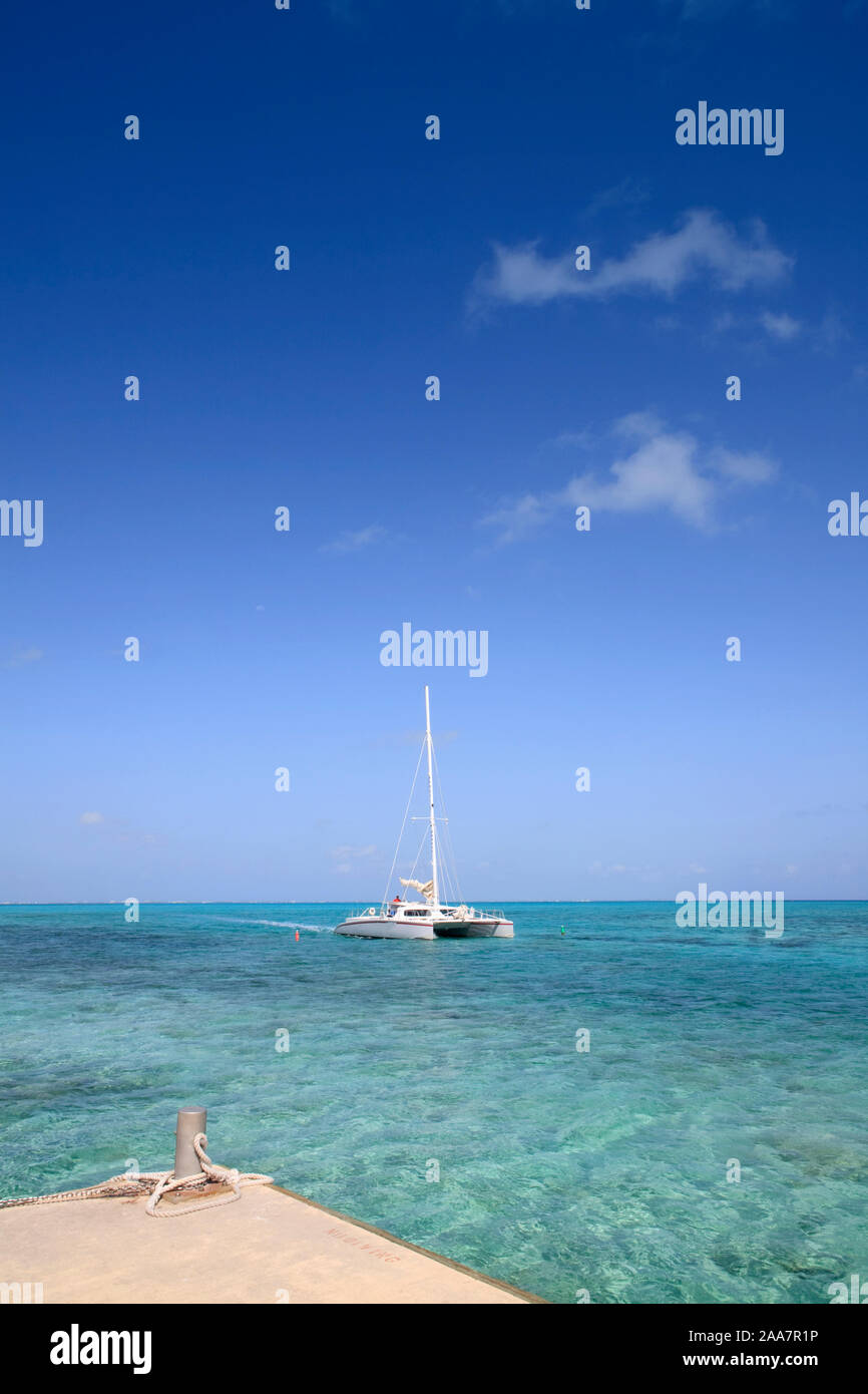Ein Katamaran rollt auf einem Pier in der Karibik mit schönen blauen Himmel und das türkisfarbene Meer. Stockfoto